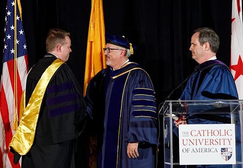Professor Kevin Walsh shaking hands with Provost Aaron Dominguez and Dean Stephen Payne
