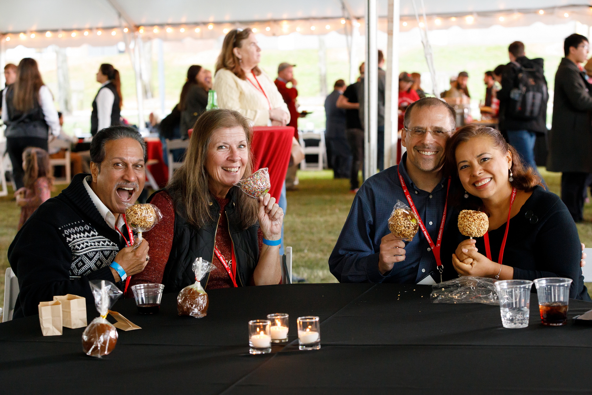 Alumni smiling with candy apples