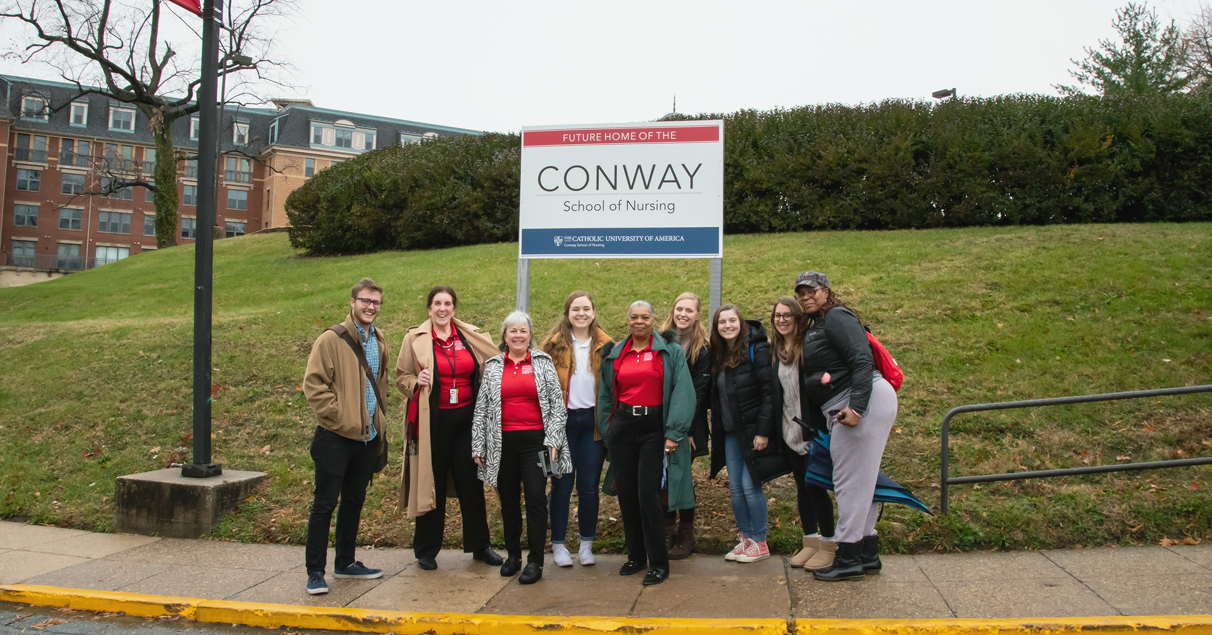 Faculty, staff, and students by the Nursing and Sciences building sign