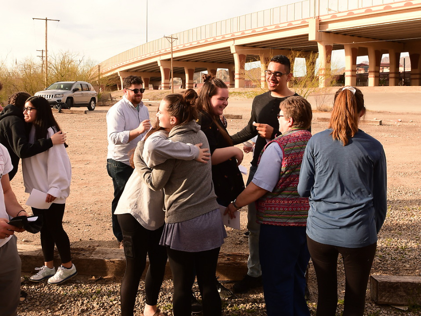 Students hugging by the border wall in El Paso