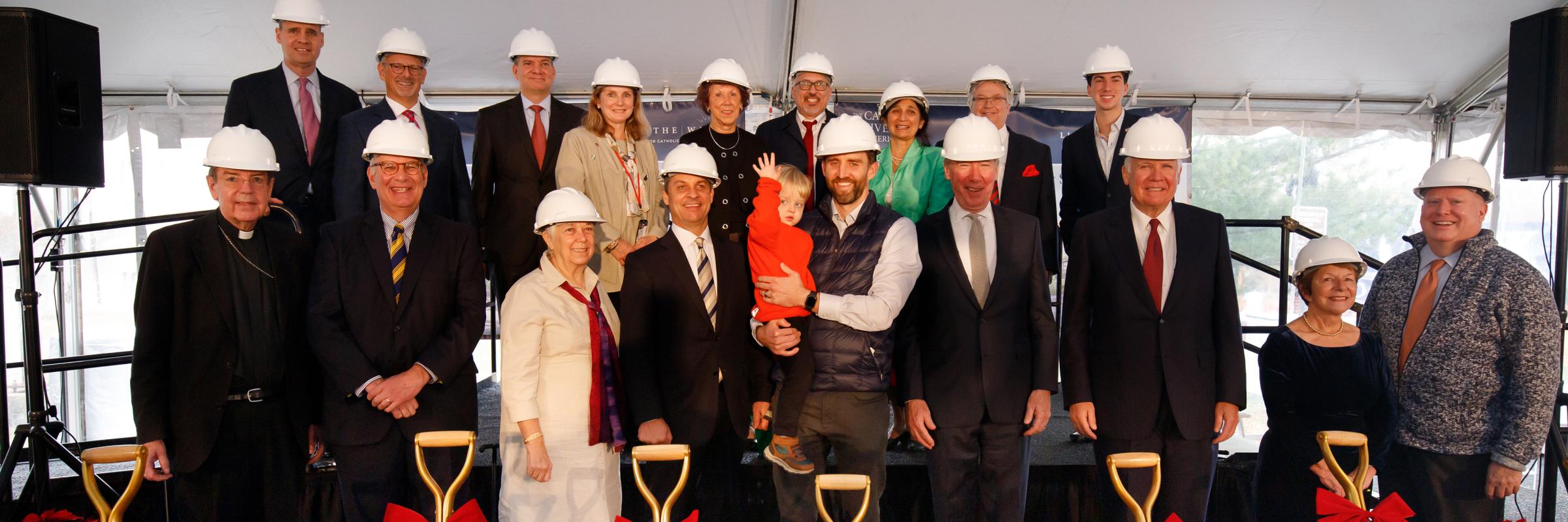 Board members, VIPs, and a child pose in front of golden shovels