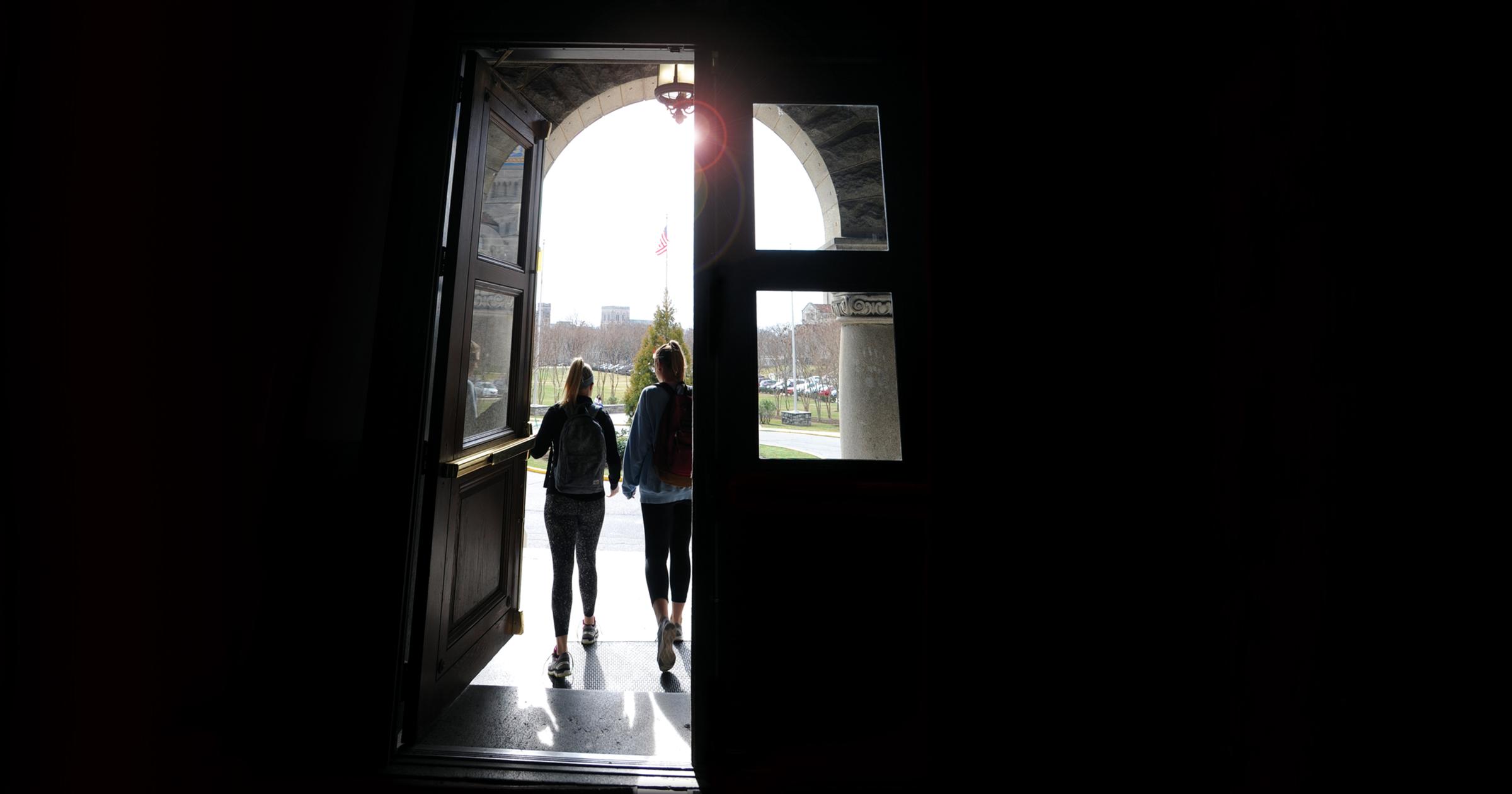 Two students walking through doors