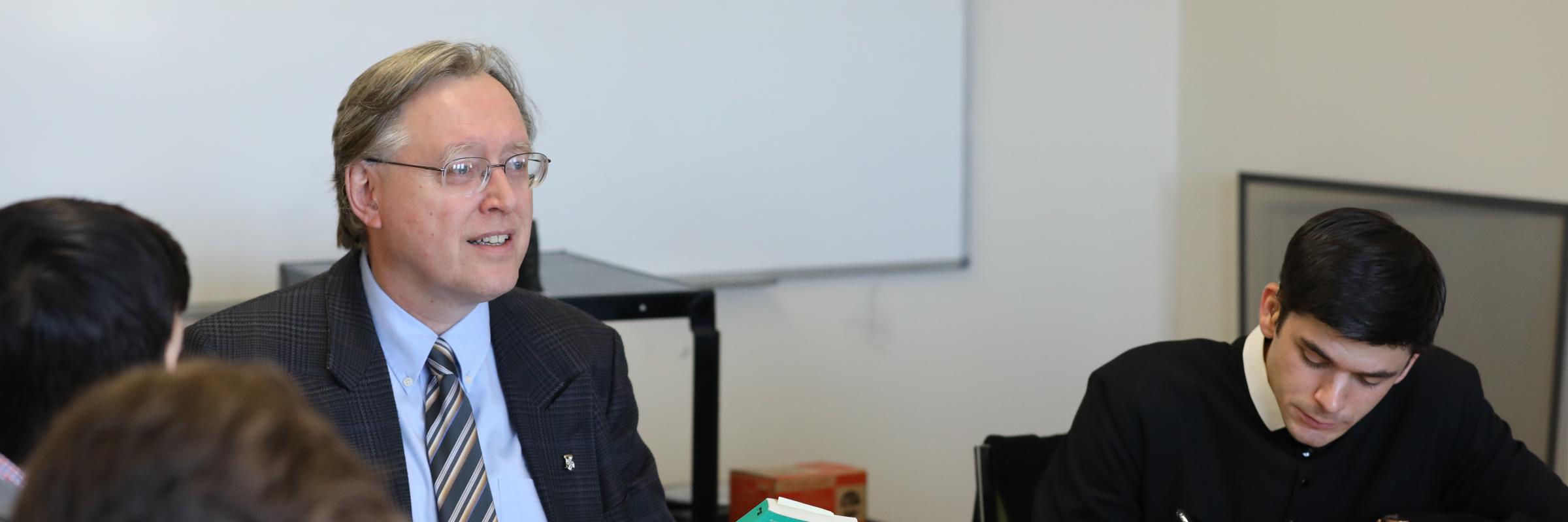 Professor teaching around a table of students 