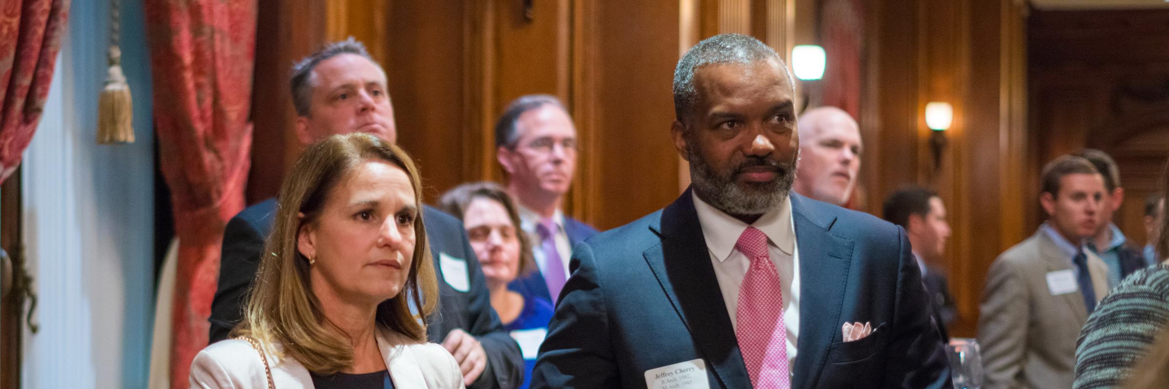 two people standing listening to speaker at a event