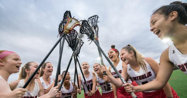 Women's lacrosse players cheer and hold their sticks high