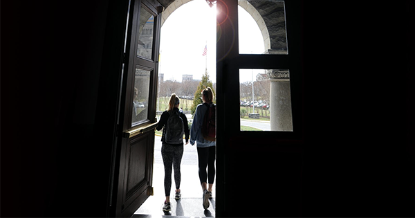 Students walk out of doorway on Catholic University's Campus