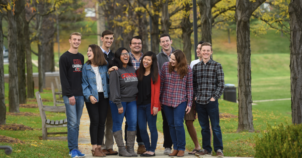 Students pose for photo outdoors on campus