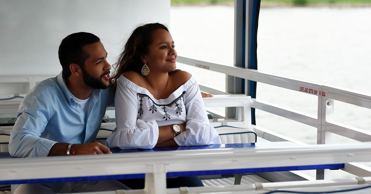A couple on a boat gazes at the calm water.