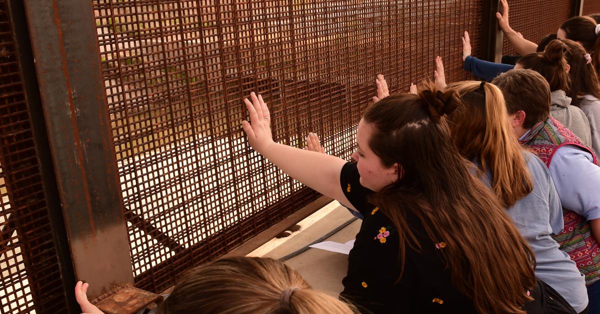 Students place their hands on the border wall